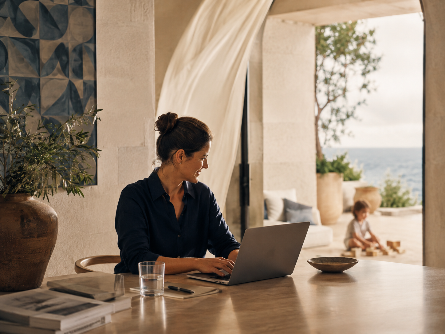 A mother working at a table while her child plays nearby